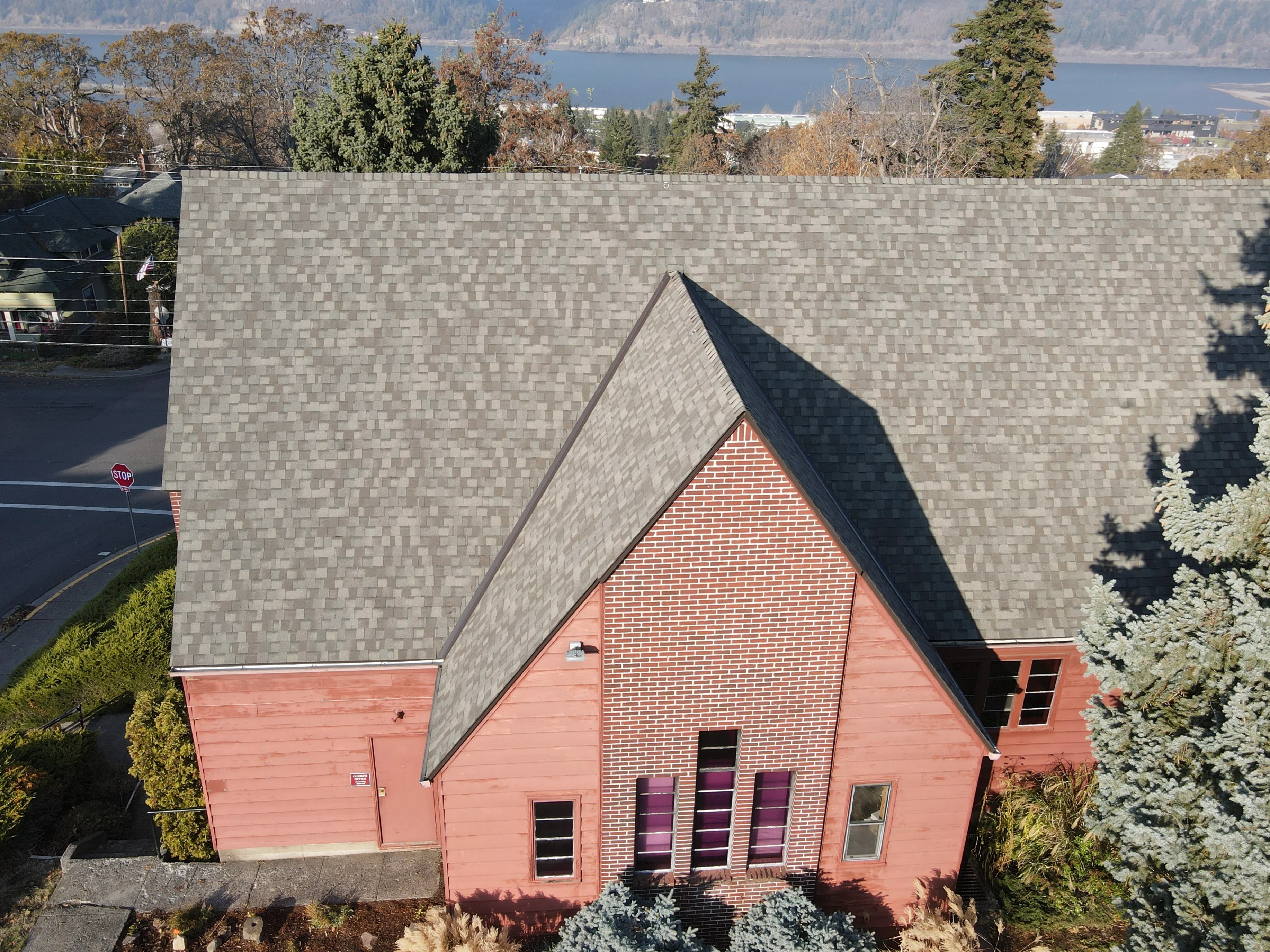 Gray architectural asphalt shingle roof installation on pitched gable structure with brick and siding