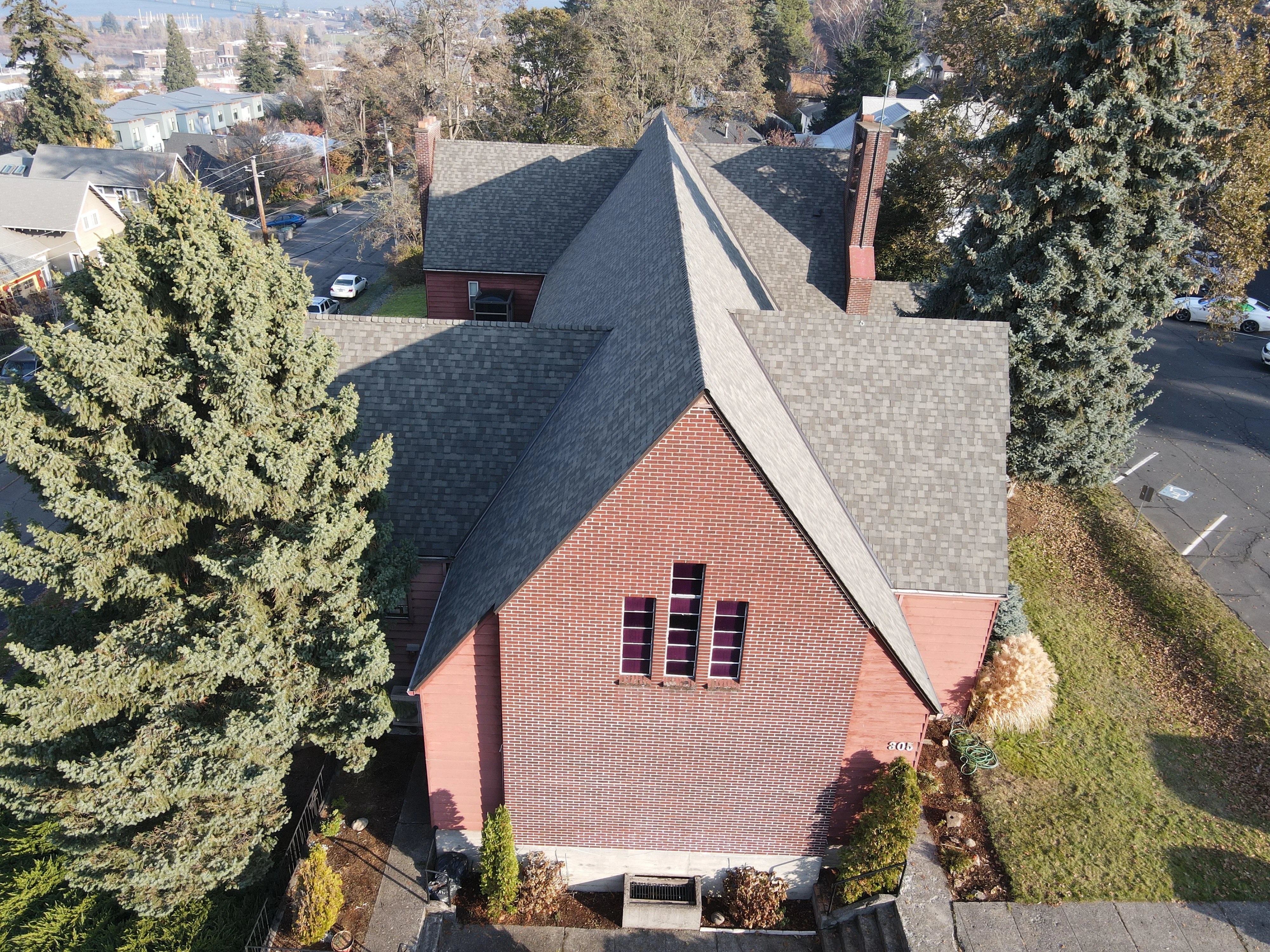 Aerial view of brick home with new charcoal gray architectural shingles on multi-plane roof