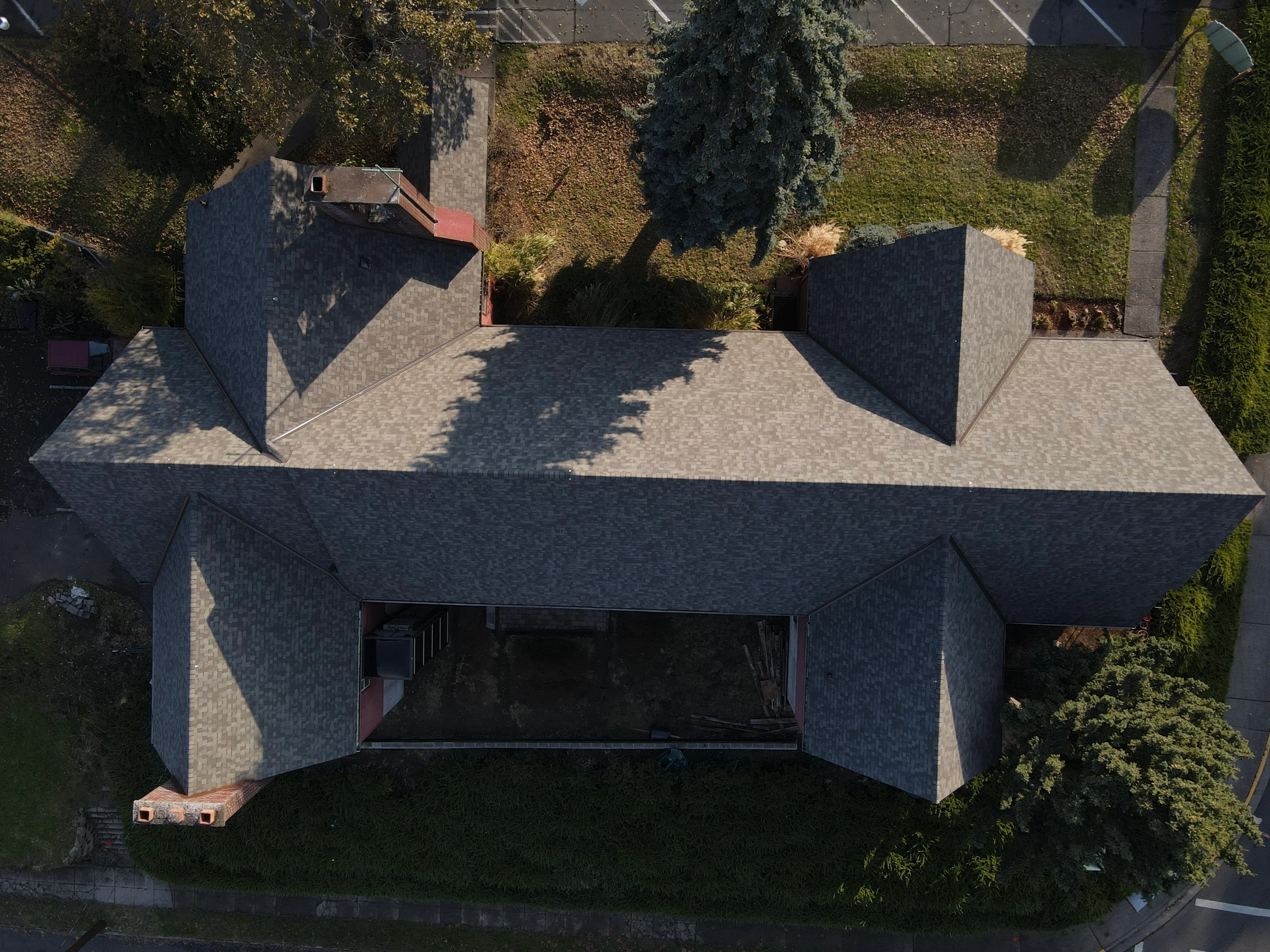 Aerial view of residential roof with charcoal gray architectural shingles on multi-pitched structure