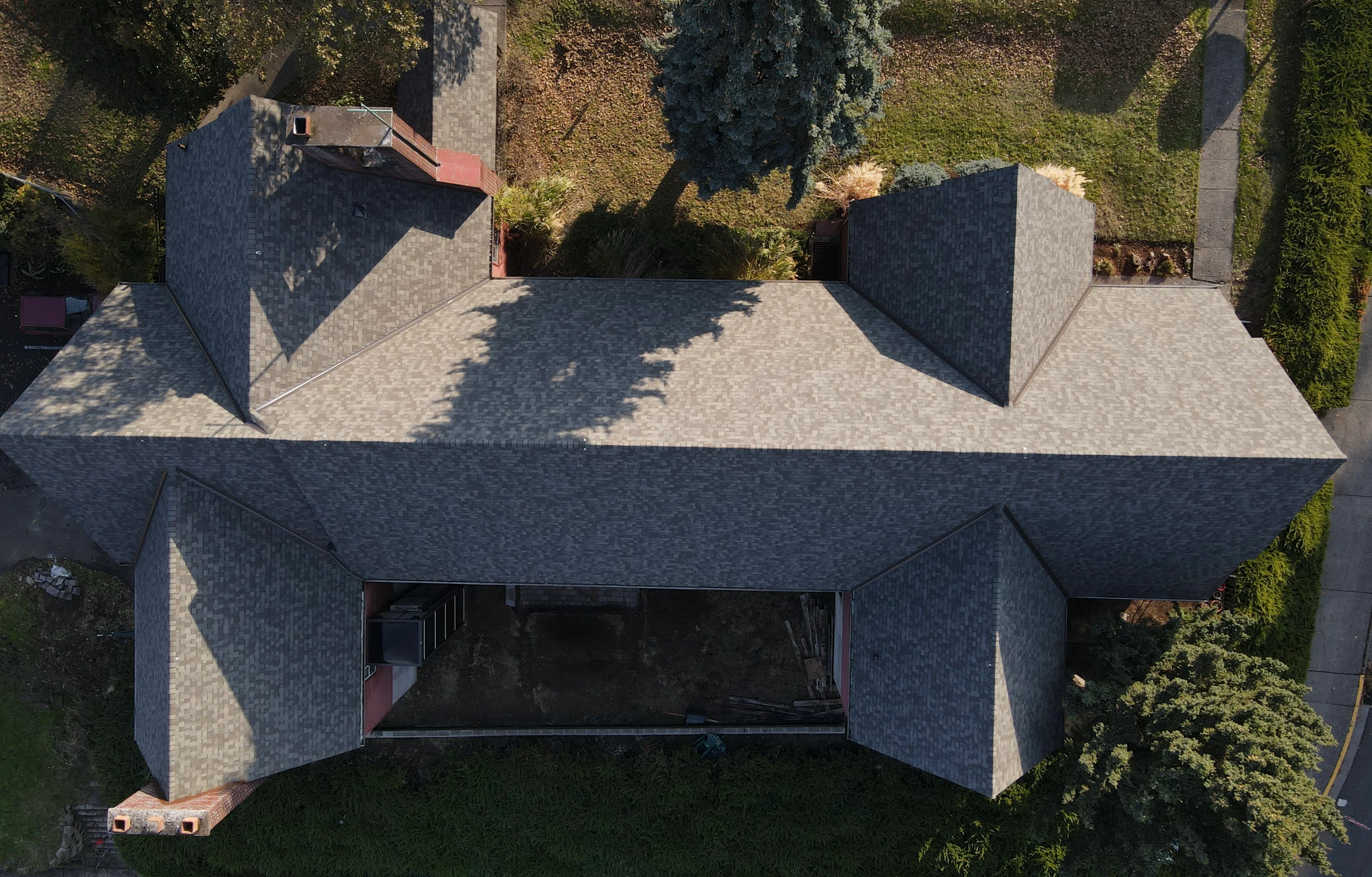 Aerial view of residential roof with charcoal gray dimensional asphalt shingles and multiple roof planes